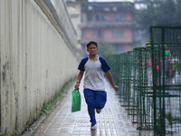 A Nepali student runs towards his home from school amid the downpour in Kathmandu, Nepal, on September 27, 2024. The Himalayan nation witnes...