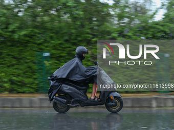 A motorcyclist wearing a raincoat drives along the roads of Kathmandu, Nepal, on September 27, 2024, following incessant rainfall and the is...