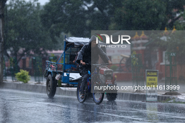 A cyclist wearing a raincoat pedals towards his destination amid the heavy downpour following a red alert from the weather department in Kat...