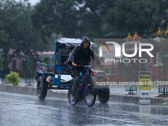 A cyclist wearing a raincoat pedals towards his destination amid the heavy downpour following a red alert from the weather department in Kat...