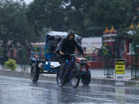 A cyclist wearing a raincoat pedals towards his destination amid the heavy downpour following a red alert from the weather department in Kat...