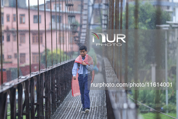 A Nepali student crosses a suspension bridge following incessant rainfall after the red alert issued by Nepal's weather department on Septem...