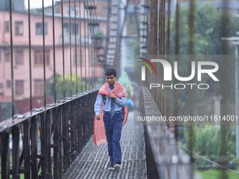 A Nepali student crosses a suspension bridge following incessant rainfall after the red alert issued by Nepal's weather department on Septem...