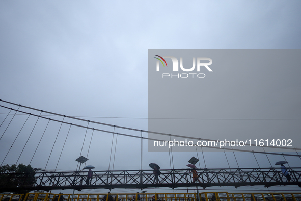 People cross a suspension bridge following incessant rainfall after the red alert issued by Nepal's weather department on September 27, 2024...