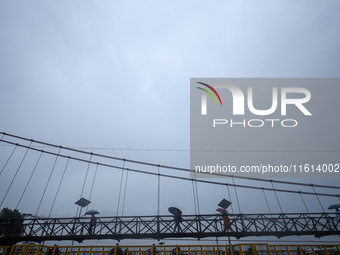 People cross a suspension bridge following incessant rainfall after the red alert issued by Nepal's weather department on September 27, 2024...