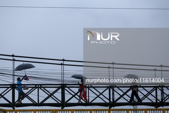 People cross a suspension bridge following incessant rainfall after the red alert issued by Nepal's weather department on September 27, 2024...