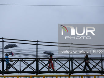 People cross a suspension bridge following incessant rainfall after the red alert issued by Nepal's weather department on September 27, 2024...