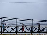 People cross a suspension bridge following incessant rainfall after the red alert issued by Nepal's weather department on September 27, 2024...