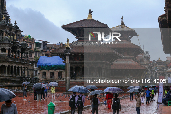 People with umbrellas walk around Patan Durbar Square, a UNESCO World Heritage Site in Lalitpur, Nepal, on September 27, 2024, after incessa...