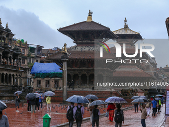 People with umbrellas walk around Patan Durbar Square, a UNESCO World Heritage Site in Lalitpur, Nepal, on September 27, 2024, after incessa...