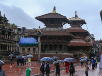 People with umbrellas walk around Patan Durbar Square, a UNESCO World Heritage Site in Lalitpur, Nepal, on September 27, 2024, after incessa...