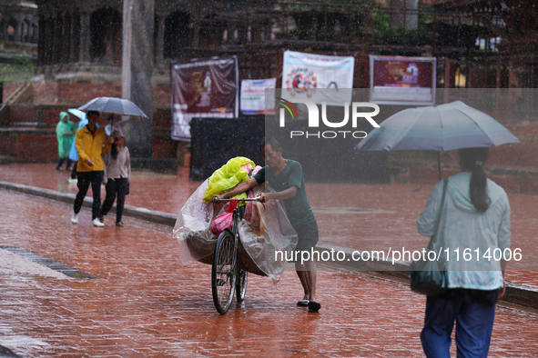 A vendor pushes his load-laden bicycle through Patan Durbar Square, a UNESCO World Heritage Site, in Patan, Nepal, on September 27, 2024, af...