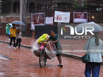 A vendor pushes his load-laden bicycle through Patan Durbar Square, a UNESCO World Heritage Site, in Patan, Nepal, on September 27, 2024, af...