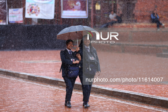 Nepali students wear umbrellas as they walk around Patan Durbar Square, a UNESCO World Heritage site in Lalitpur, Nepal, on September 27, 20...