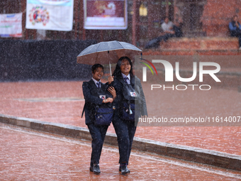 Nepali students wear umbrellas as they walk around Patan Durbar Square, a UNESCO World Heritage site in Lalitpur, Nepal, on September 27, 20...