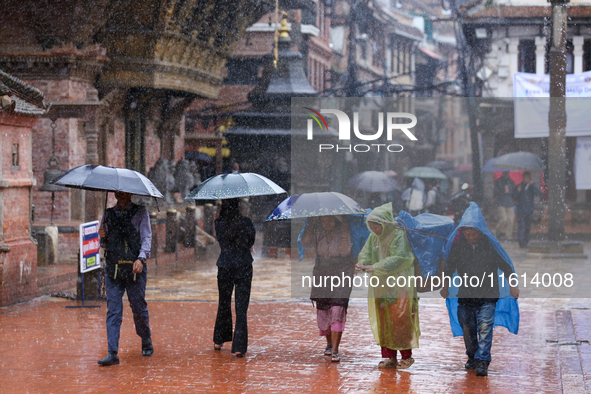 People with umbrellas walk around Patan Durbar Square, a UNESCO World Heritage Site in Lalitpur, Nepal, on September 27, 2024, after incessa...