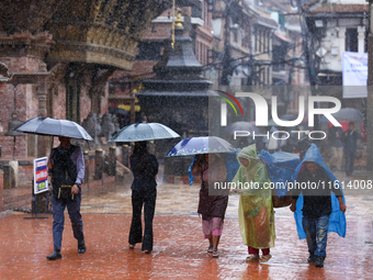 People with umbrellas walk around Patan Durbar Square, a UNESCO World Heritage Site in Lalitpur, Nepal, on September 27, 2024, after incessa...