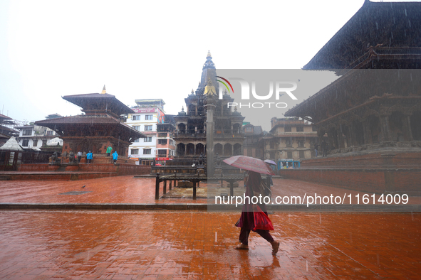 A Nepali woman wearing an umbrella walks around Patan Durbar Square, a UNESCO World Heritage Site in Lalitpur, Nepal, on September 27, 2024,...