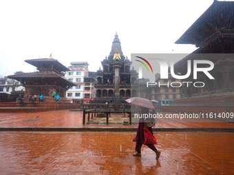 A Nepali woman wearing an umbrella walks around Patan Durbar Square, a UNESCO World Heritage Site in Lalitpur, Nepal, on September 27, 2024,...