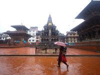 A Nepali woman wearing an umbrella walks around Patan Durbar Square, a UNESCO World Heritage Site in Lalitpur, Nepal, on September 27, 2024,...