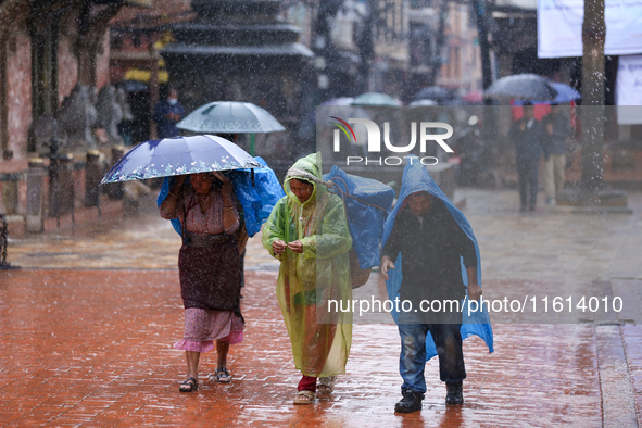 People with umbrellas walk around Patan Durbar Square, a UNESCO World Heritage Site in Lalitpur, Nepal, on September 27, 2024, after incessa...