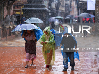 People with umbrellas walk around Patan Durbar Square, a UNESCO World Heritage Site in Lalitpur, Nepal, on September 27, 2024, after incessa...