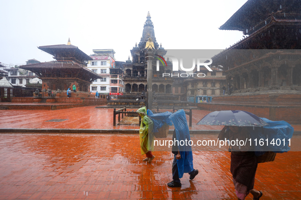 People with umbrellas walk around Patan Durbar Square, a UNESCO World Heritage Site in Lalitpur, Nepal, on September 27, 2024, after incessa...