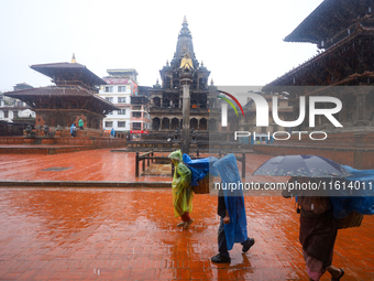 People with umbrellas walk around Patan Durbar Square, a UNESCO World Heritage Site in Lalitpur, Nepal, on September 27, 2024, after incessa...