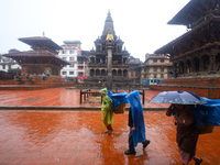 People with umbrellas walk around Patan Durbar Square, a UNESCO World Heritage Site in Lalitpur, Nepal, on September 27, 2024, after incessa...