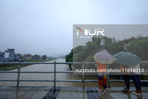 People watch the swollen Bagmati River from a bridge in Kathmandu, Nepal, on September 27, 2024. The Himalayan nation witnesses downpour aft...