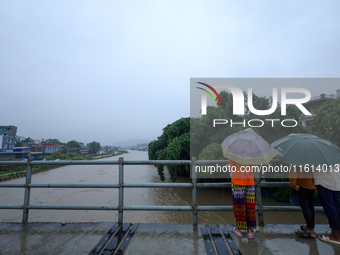 People watch the swollen Bagmati River from a bridge in Kathmandu, Nepal, on September 27, 2024. The Himalayan nation witnesses downpour aft...