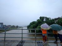 People watch the swollen Bagmati River from a bridge in Kathmandu, Nepal, on September 27, 2024. The Himalayan nation witnesses downpour aft...