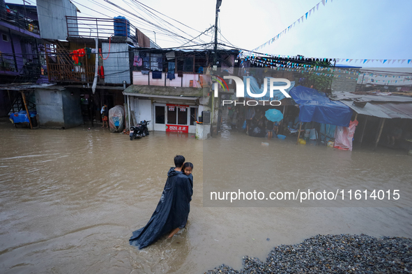 A man carries his daughter in his arms as he wades through the flooded water in Kathmandu, Nepal, on September 27, 2024. The Himalayan natio...