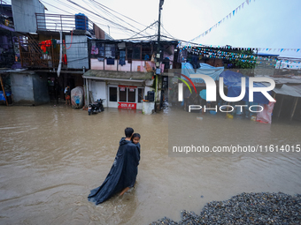 A man carries his daughter in his arms as he wades through the flooded water in Kathmandu, Nepal, on September 27, 2024. The Himalayan natio...