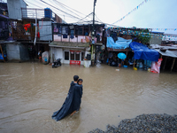 A man carries his daughter in his arms as he wades through the flooded water in Kathmandu, Nepal, on September 27, 2024. The Himalayan natio...