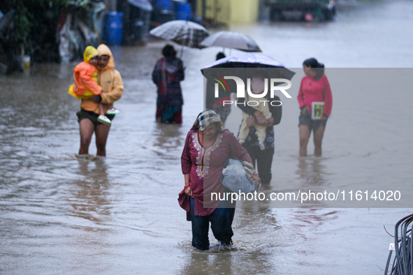 People move to higher ground carrying their belongings, wading through the floodwater in Kathmandu, Nepal, on September 27, 2024. The Himala...