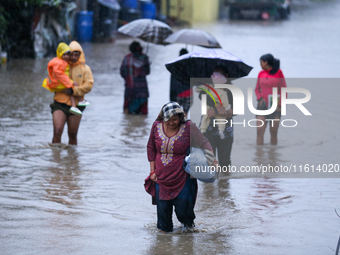 People move to higher ground carrying their belongings, wading through the floodwater in Kathmandu, Nepal, on September 27, 2024. The Himala...