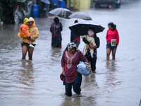 People move to higher ground carrying their belongings, wading through the floodwater in Kathmandu, Nepal, on September 27, 2024. The Himala...