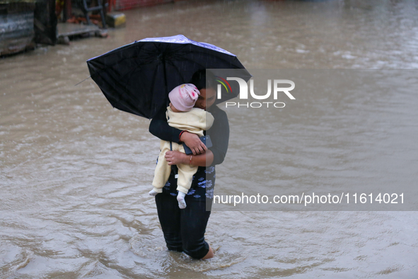 A Nepali woman carries a baby and wades through floodwater in Kathmandu, Nepal, on September 27, 2024. The Himalayan nation witnesses downpo...