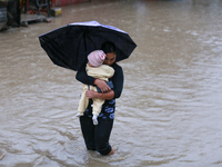 A Nepali woman carries a baby and wades through floodwater in Kathmandu, Nepal, on September 27, 2024. The Himalayan nation witnesses downpo...