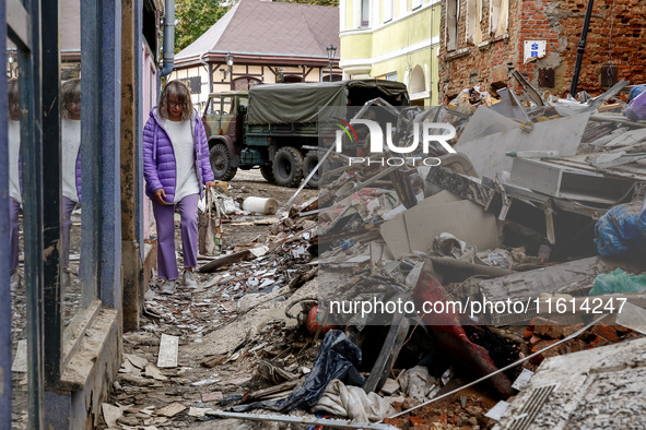 A woman walks pass debris from destroyed  buildings as massive flooding affected tourist resorts in southern Poland - Klodzko, Poland on Sep...