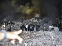 People watch as a blaze rages amid the smoldering rubble of a building destroyed in an Israeli air strike in the Haret Hreik neighborhood of...