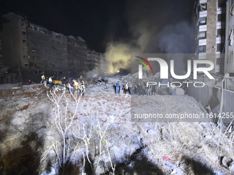 People watch as a blaze rages amid the smoldering rubble of a building destroyed in an Israeli air strike in the Haret Hreik neighborhood of...