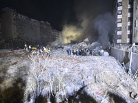 People watch as a blaze rages amid the smoldering rubble of a building destroyed in an Israeli air strike in the Haret Hreik neighborhood of...