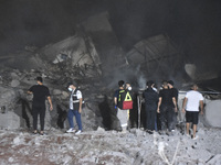 People watch as a blaze rages amid the smoldering rubble of a building destroyed in an Israeli air strike in the Haret Hreik neighborhood of...