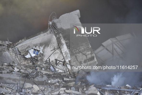 People watch as a blaze rages amid the smoldering rubble of a building destroyed in an Israeli air strike in the Haret Hreik neighborhood of...