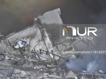 People watch as a blaze rages amid the smoldering rubble of a building destroyed in an Israeli air strike in the Haret Hreik neighborhood of...