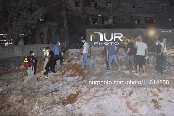 People watch as a blaze rages amid the smoldering rubble of a building destroyed in an Israeli air strike in the Haret Hreik neighborhood of...