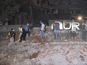 People watch as a blaze rages amid the smoldering rubble of a building destroyed in an Israeli air strike in the Haret Hreik neighborhood of...