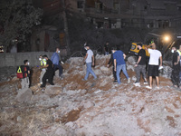 People watch as a blaze rages amid the smoldering rubble of a building destroyed in an Israeli air strike in the Haret Hreik neighborhood of...